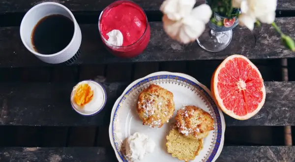 Frukost med kaffe, en rosa smoothie, ett kokt ägg, grapefrukt och nybakade mandelscones.