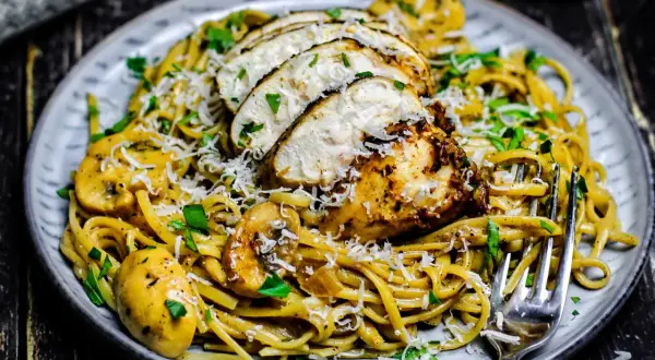 Ein Teller cremiger Pasta mit gebratenem Hähnchen, Pilzen und Parmesan. Dieses Chicken Alfredo Gericht sieht köstlich aus.