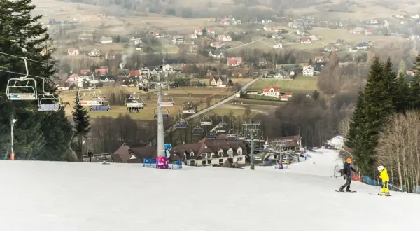 Hotel ze stokiem narciarskim dla dzieci. Kolejka krzesełkowa wwozi narciarzy na szczyt, skąd zjeżdżają po ośnieżonym stoku.