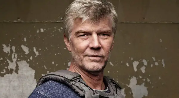 Johan Falk i ny film. En man med grått hår och väst ser allvarlig ut.