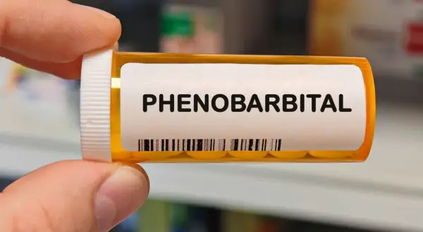 Pudełko z lekami z napisem "PHENO BARBITAL". Zawiera tabletki, które należą do grupy barbituranów.