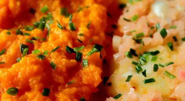 Purée de carotte onctueuse, parsemée de ciboulette fraîche, à côté d'un plat de poisson aux oignons roses. Un délice coloré.