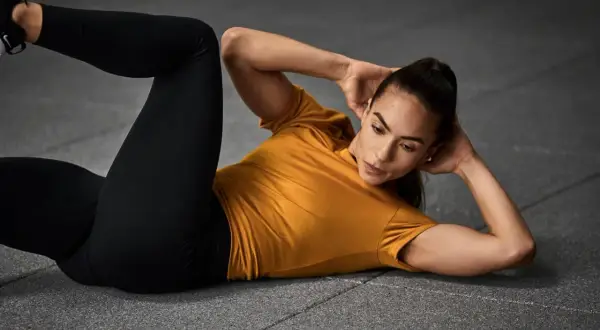 Frau macht Crunches, eine Übung für die Bauchmuskeln, auf dem Boden liegend.