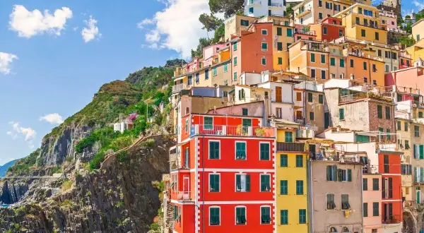 Färgstarka hus klättrar uppför en brant sluttning vid kusten i Italien. En vy som inbjuder till dricks i Italien.