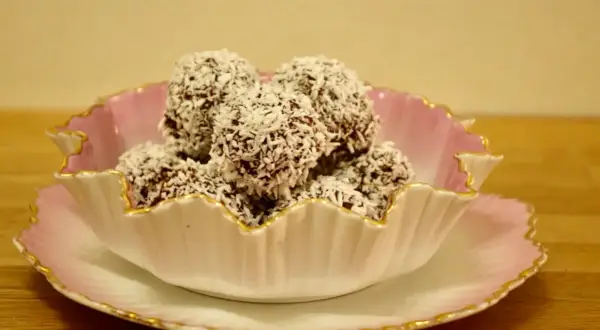 En skål med chokladbollar, perfekta för ett enkelt delicatobollar recept. Kokosflingor täcker de mörka bollarna.