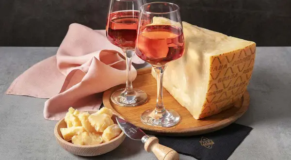 Un bicchiere di vino rosato e un pezzo di Grana Padano, un abbinamento perfetto per un aperitivo.