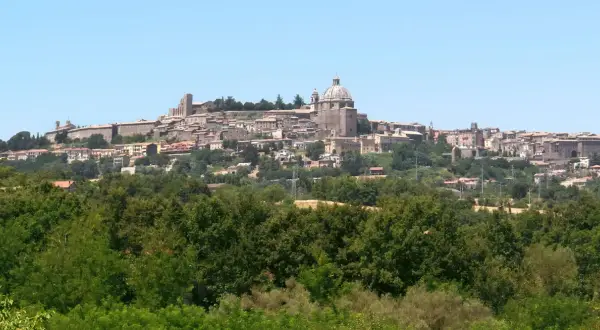 Vista panoramica di Montefiascone, con il suo imponente centro storico arroccato su una collina, che domina il paesaggio verso il lago di Bolsena.