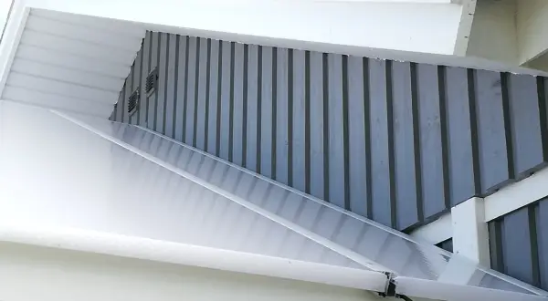 Taket på ett uterum som byggs mot en fasad. Genomskinlig plasttak med grå träpanel bakom.