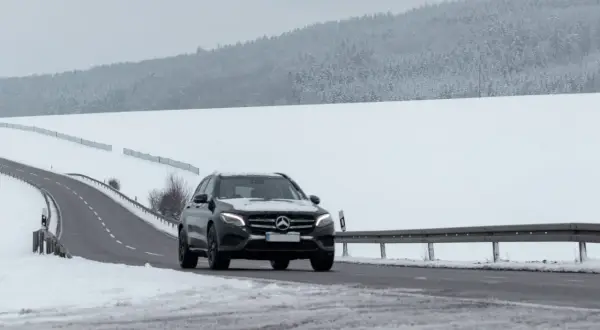 Czarny Mercedes GLE jedzie po ośnieżonej drodze. Jego wymiary pozwalają na pewne poruszanie się w trudnych warunkach.