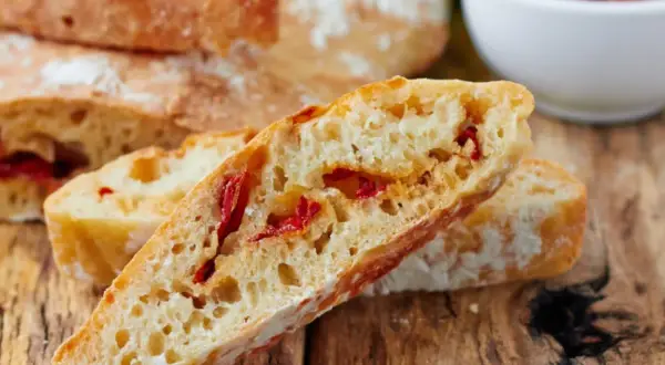 Frisches Ciabatta mit Tomaten, auf einem rustikalen Holztisch.