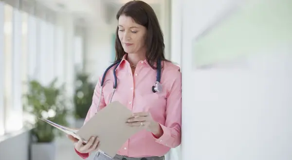 Médecin consultant un dossier, peut-être pour un deuxième avis médical et son remboursement.