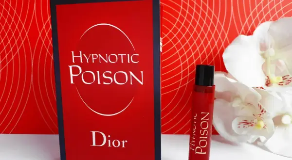 Kuszący zapach Christian Dior Hypnotic Poison w czerwonym flakonie obok karty z nazwą.