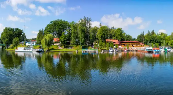 Malowniczy widok na port w Rucianem Nidzie, gdzie cumują łodzie i statki. To idealne miejsce na odkrywanie urokliwych atrakcji Mazur.