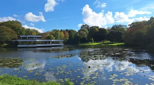 Ein moderner Bau am Ufer eines Teichs mit Seerosen, umgeben von Bäumen. Ein friedlicher Ort, der zeigt, was man in Bremen gesehen haben muss.