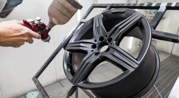 Un professionista mostra come verniciare i cerchi in lega con uno spray gun, dando un nuovo look all'auto.