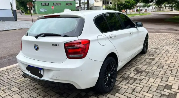 Vit vit BMW 118i står parkerad på en stenlagd uppfart. Kanske ett problem med bilen?