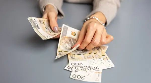 Dłonie liczą banknoty 200 zł, przygotowując świadczenie urlopowe.