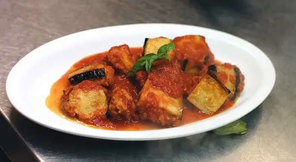 Friterad aubergine i tomatsås, toppad med färsk basilika. En läcker italiensk rätt.