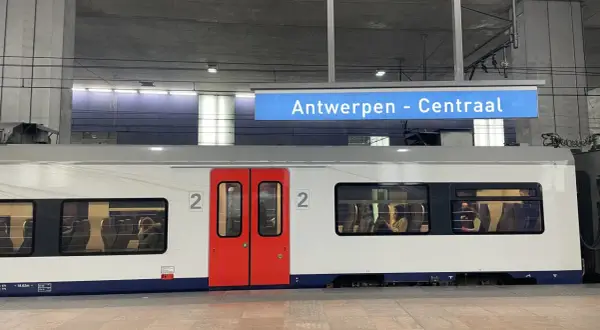Pociągiem po Europie: biały wagon z czerwonymi drzwiami na stacji Antwerpen - Centraal. W oknach widać pasażerów.