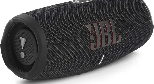Czarny głośnik JBL z czerwonym logo. Dowiedz się, jak podłączyć słuchawki JBL z iPhone, by cieszyć się muzyką.