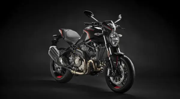 Czarny motocykl Ducati Monster na ciemnym tle.