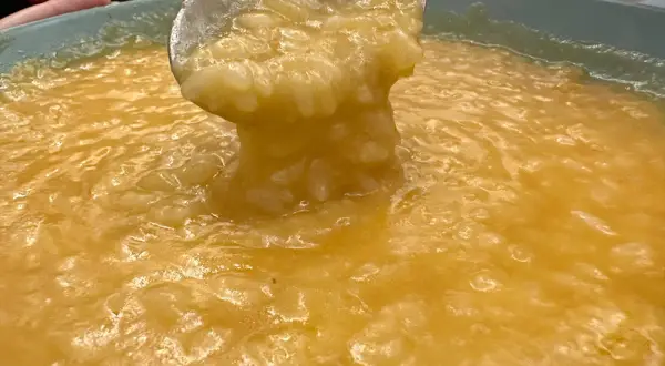 Un mestolo solleva una porzione cremosa di riso e patate, un piatto confortante e dorato.