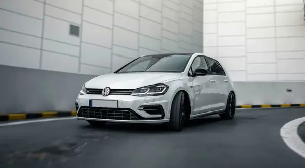 Vit Volkswagen Golf R, en bil som kan drabbas av 1.4 TSI-problem, kör på en asfalterad väg.
