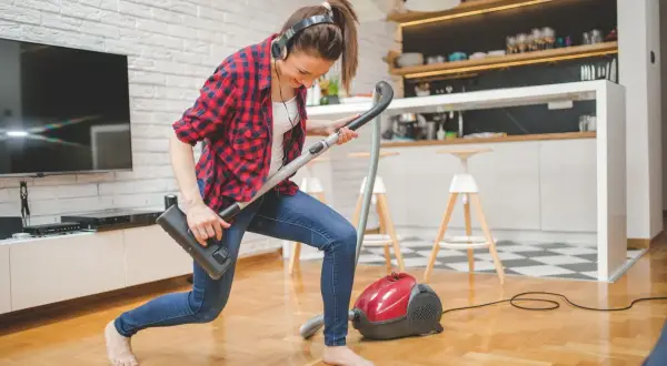 Frau mit Kopfhörern spielt Staubsauger-Gitarre. So macht **family fitness** Spaß!