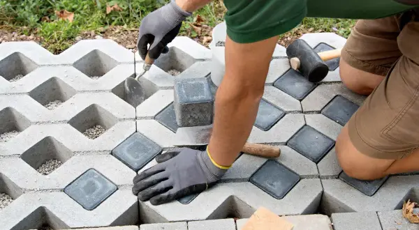 Gartenarbeit: Rasengittersteine für eine stabile Einfahrt werden verlegt. Ein Handwerker setzt die Steine präzise ein.