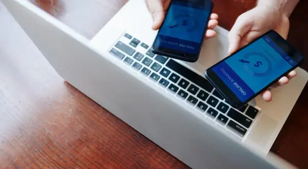 Dwie dłonie trzymają telefony z aplikacją bankową. Szybka **paypal wypłata blik** to teraz norma.