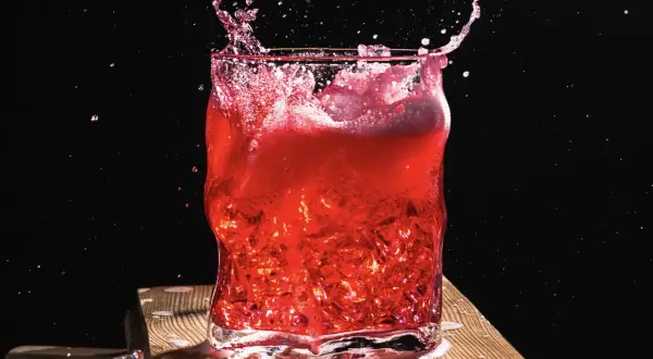 Intensywny drink z wiśniówką w szkle, z rozpryskującym się płynem i lodem.
