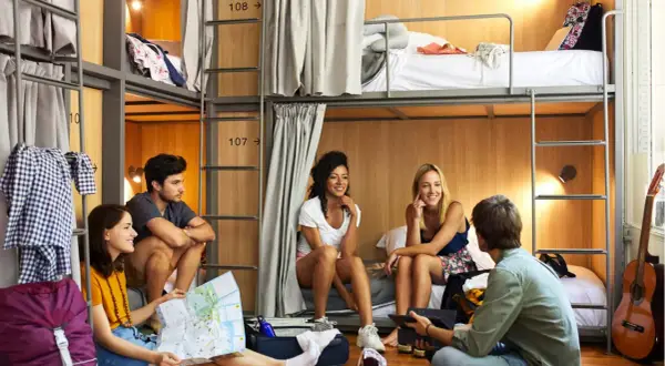 Jóvenes planean su viaje en un hostal, con literas y un ambiente social.