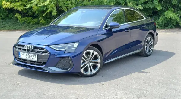 Elegancki, granatowy Audi A3 2025 sedan na tle zieleni.