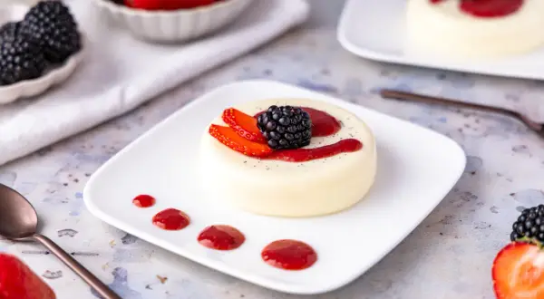 Cremige Panna Cotta, perfekt zubereitet im Thermomix, garniert mit frischen Beeren und Erdbeersauce. Ein Genuss für Augen und Gaumen.