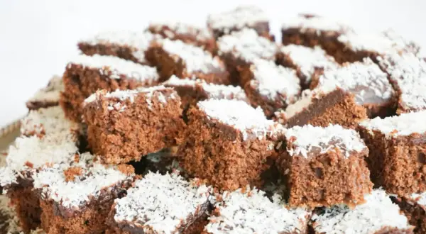 En hög med små, fyrkantiga chokladbitar, en klassisk snoddas kaka, toppade med kokosflingor.