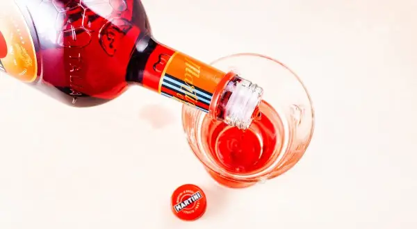 Czerwony Martini Fiero Prosecco nalewany do kieliszka. Obok leży zakrętka.