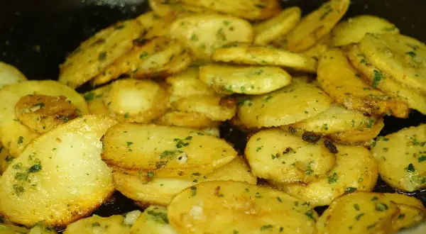 Patatas panaderas al horno crujientes, doradas y con perejil picado, listas para disfrutar.