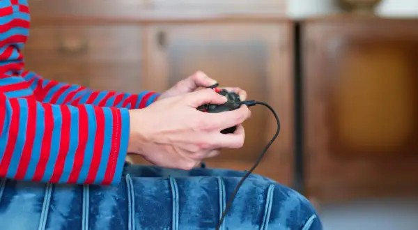 Ręce trzymające kontroler, gotowe do gry. Dowiedz się, jak podłączyć Nintendo do TV i rozpocząć przygodę!