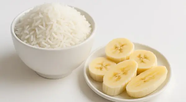 Riso bianco in una ciotola e fette di banana su un piattino, ingredienti ideali per una dieta astringente.