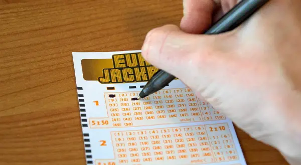Ręka zaznacza liczby na kuponie Eurojackpot. Zastanawiasz się, dlaczego w Polsce nie można grać w Eurojackpot anonimowo przez pełnomocnika?