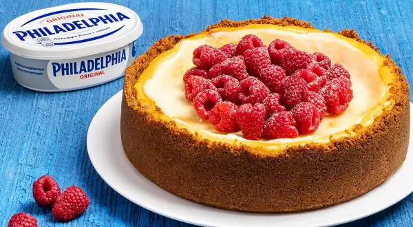 New York cheesecake con lamponi freschi, accanto a un vasetto di Philadelphia Original.