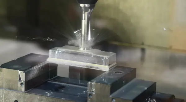 Precyzyjne frezowanie aluminium na maszynie CNC. Chłodziwo rozpryskuje się wokół obrabianego elementu.
