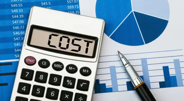 Kalkulator z napisem "COST" na tle wykresów i tabel, symbolizujący analizę i redukcję kosztów.