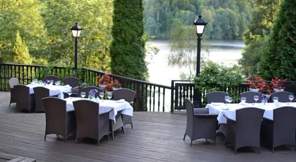 Elegancki taras z nakrytymi stołami i widokiem na jezioro. Idealne miejsce na relaks w spa na Mazurach.