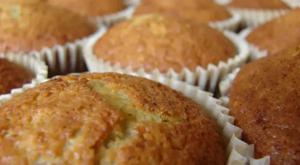 En närbild på flera gyllene bananmuffins utan socker i sina pappersformar. De ser saftiga och hembakade ut.