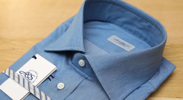 Camicia azzurra con colletto button down, etichetta e nastro a righe.