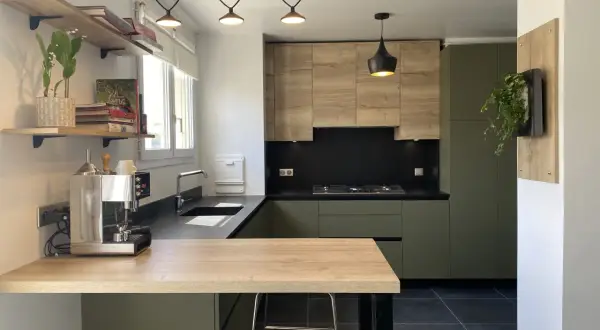 Cuisine moderne avec meubles verts et bois, plan de travail noir et îlot en bois.