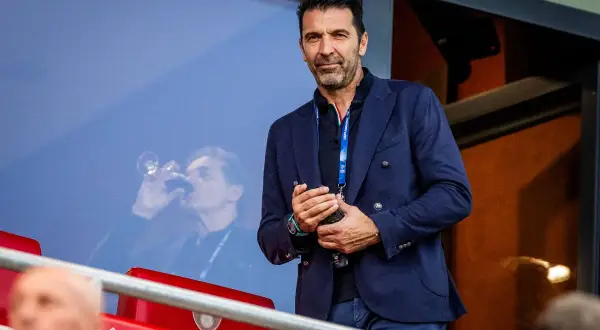 Gianluigi Buffon, legendarny bramkarz włoski, w eleganckim garniturze, obserwuje mecz z trybun.