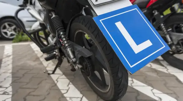 Motocykl z tabliczką "L" - symbol nauki jazdy, przygotowany do zdobycia prawa jazdy na motocykl.