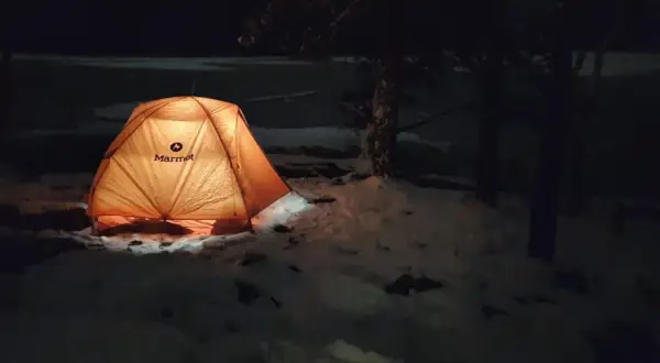 Upplyst tält i snön, redo för att sova ute på vintern.